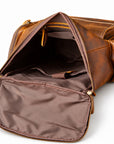 An open brown leather bag with gold-tone zippers, showing a dark brown interior lining and organized compartments.