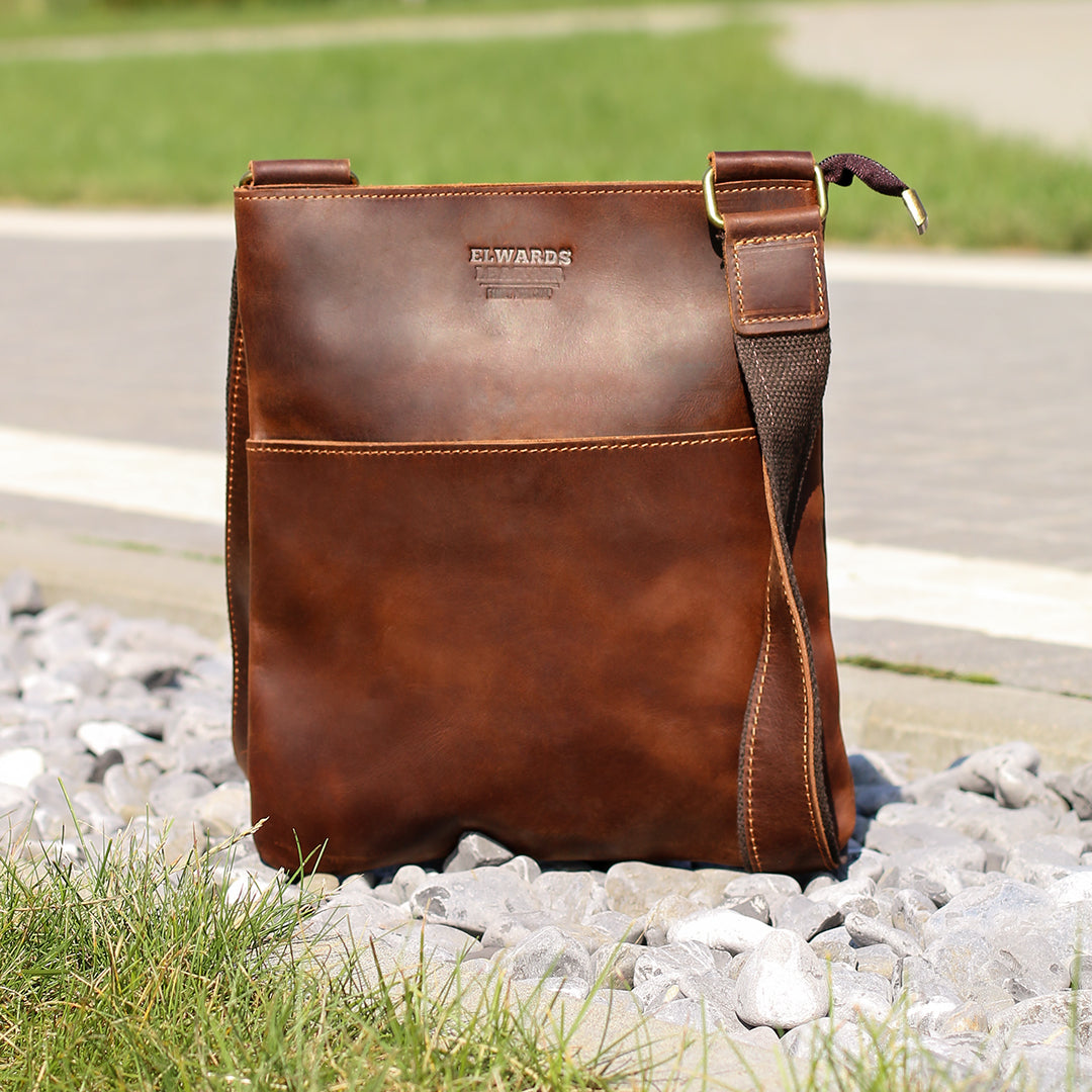 Brown Crazy Horse leather crossbody bag on gravel, featuring clean lines and detailed hand-stitching.