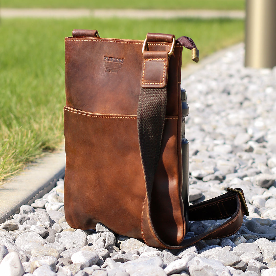 Brown Crazy Horse leather crossbody bag on gravel, emphasizing its durability and vintage style.