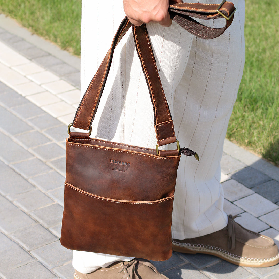 Close-up of a man holding a brown Crazy Horse leather crossbody bag, emphasizing its compact size and premium craftsmanship.