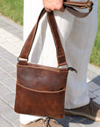 Close-up of a man holding a brown Crazy Horse leather crossbody bag, emphasizing its compact size and premium craftsmanship.