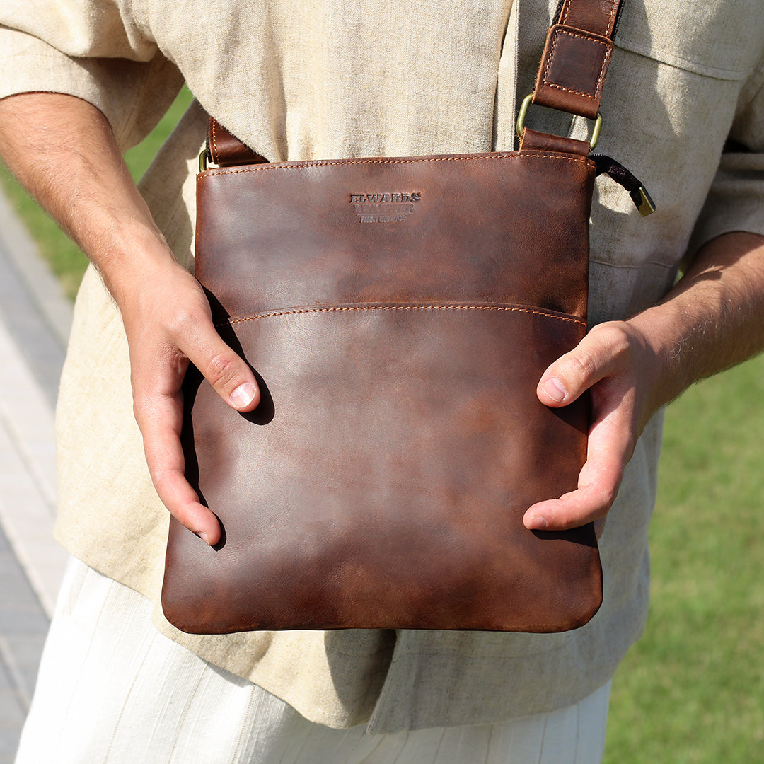 Man holding a brown Crazy Horse leather crossbody bag, showcasing its premium quality and versatile design.