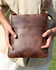 Man holding a brown Crazy Horse leather crossbody bag, showcasing its premium quality and versatile design.