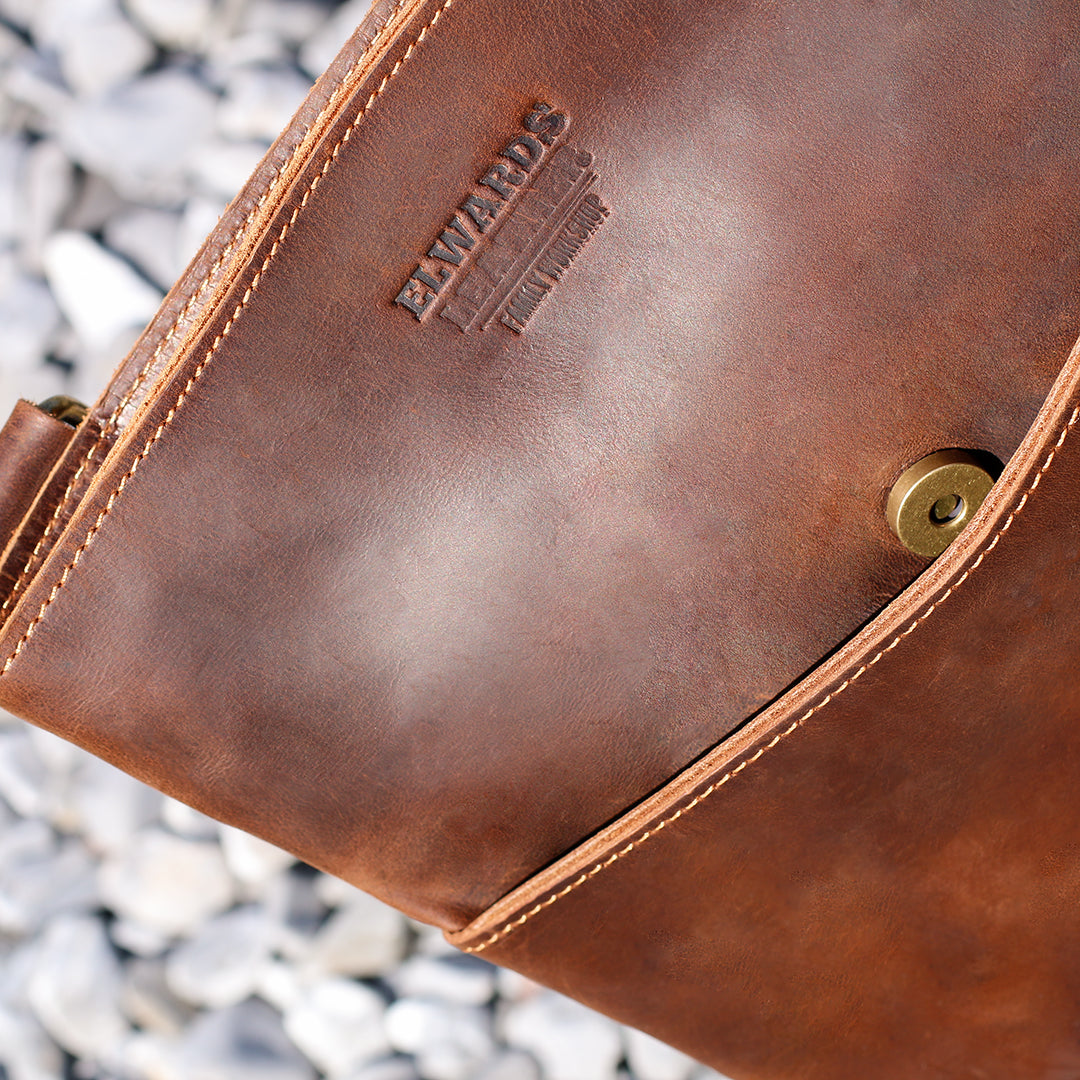 Close-up of the pocket and logo on a brown Crazy Horse leather crossbody bag, showcasing vintage style.