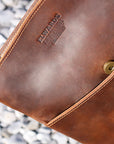 Close-up of the pocket and logo on a brown Crazy Horse leather crossbody bag, showcasing vintage style.