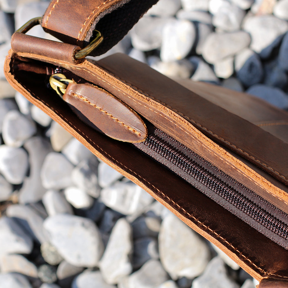 Close-up of the zipper on a brown Crazy Horse leather crossbody bag, showcasing durability and precise stitching.