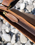 Close-up of the zipper on a brown Crazy Horse leather crossbody bag, showcasing durability and precise stitching.