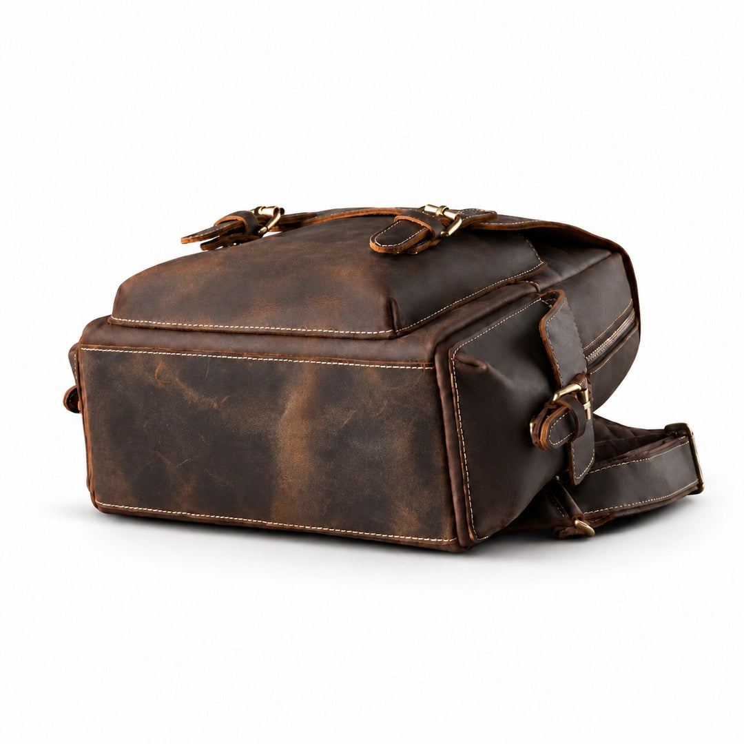 A dark brown distressed leather crossbody bag with brass hardware, shown from a three-quarters angle.