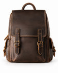 A dark brown distressed leather backpack with two front buckle straps, a top handle, and side pockets.