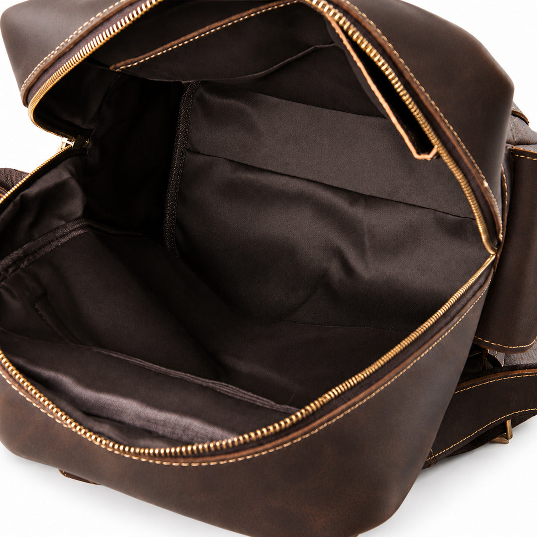 Close-up of an open dark brown leather bag showing the interior lining, gold-toned zipper, and stitching details.