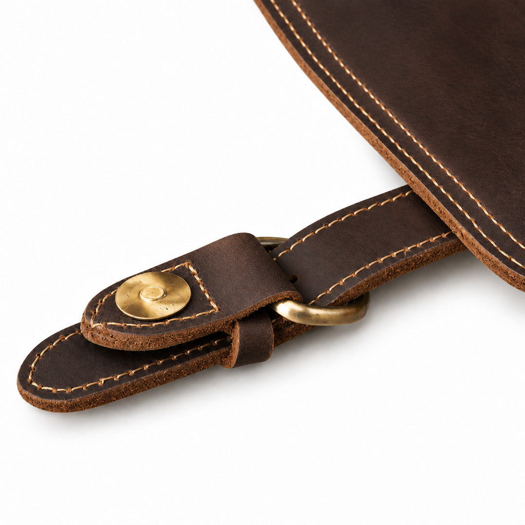 Close-up of a dark brown leather strap with tan stitching, a brass snap button, and a brass ring.
