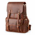 A brown leather backpack with a front flap, buckle straps, and multiple pockets, photographed.