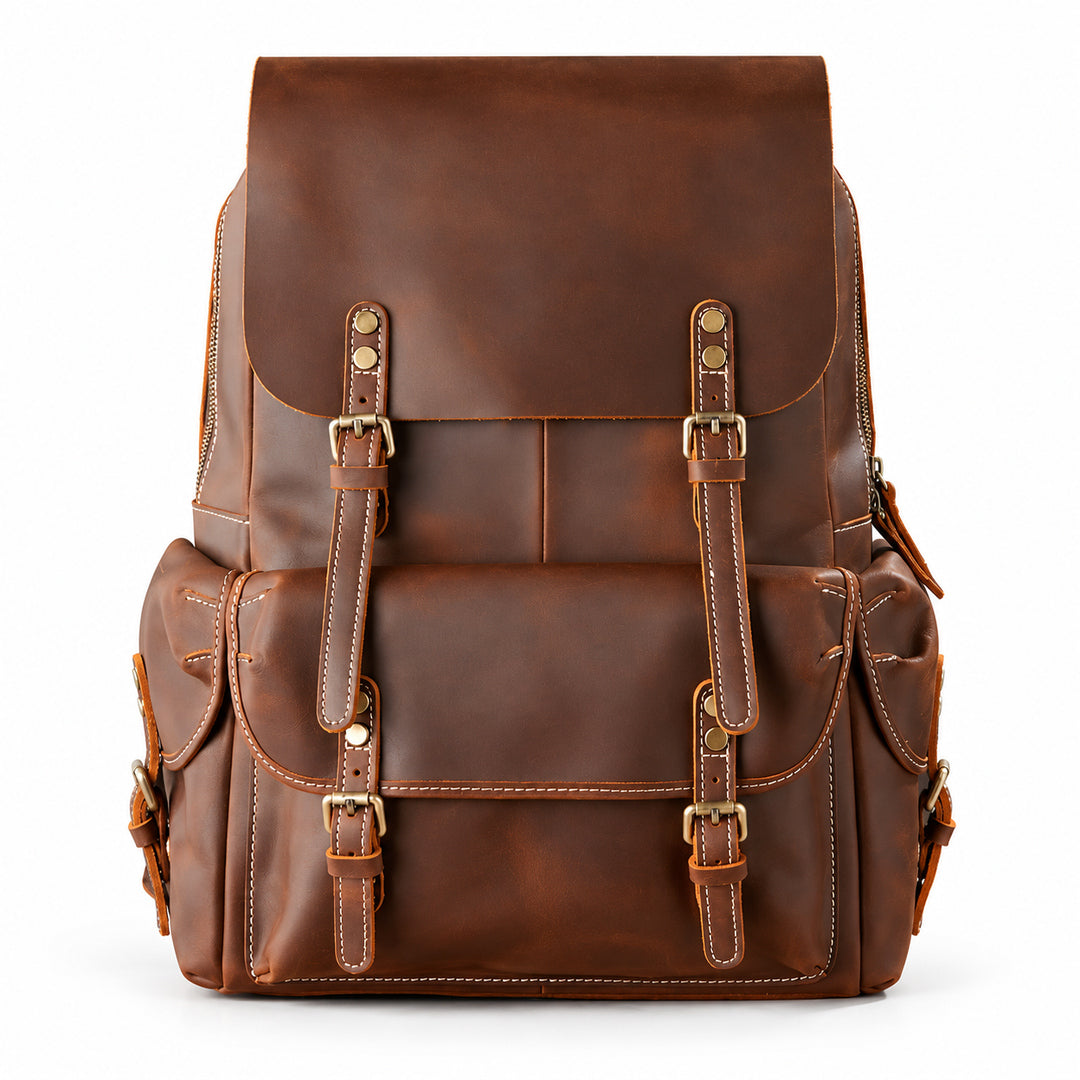 A brown leather backpack with front buckle straps and multiple pockets, photographed against.