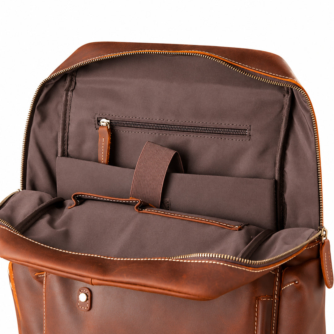 Open brown leather briefcase or duffel bag showing the interior organization with a dark brown fabric lining, zip pocket, elastic strap, and storage compartments.