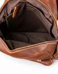 An open brown leather backpack or messenger bag showing the interior lining, gold-tone zippers, and stitching details.