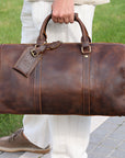 Luxury brown leather duffle bag carried by hand, perfect for stylish and practical travel.