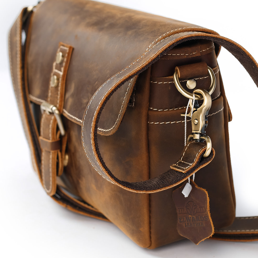 Brown leather satchel bag with gold accents on a white background