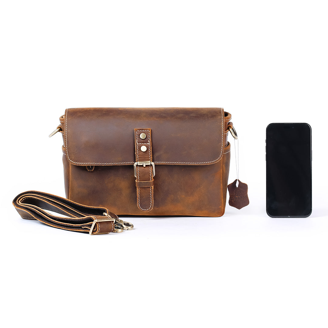 Brown leather bag with strap and smartphone on a white background