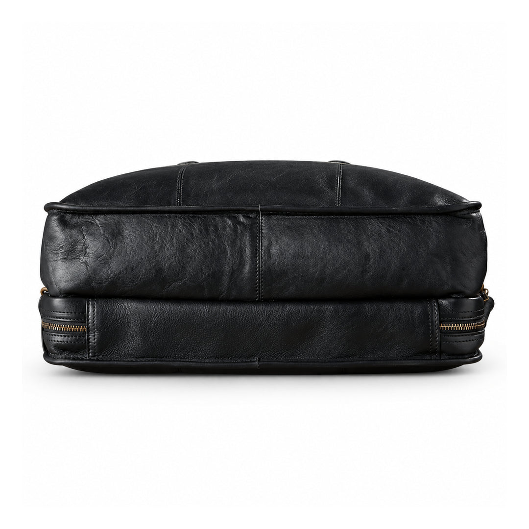 The underside of a black leather briefcase shows its two-section construction, central seam and piped edges.