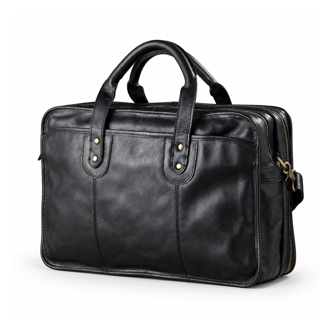 A black leather briefcase is shown in a front three-quarter view with rounded handles, paired brass-tone rivets and two zip compartments.
