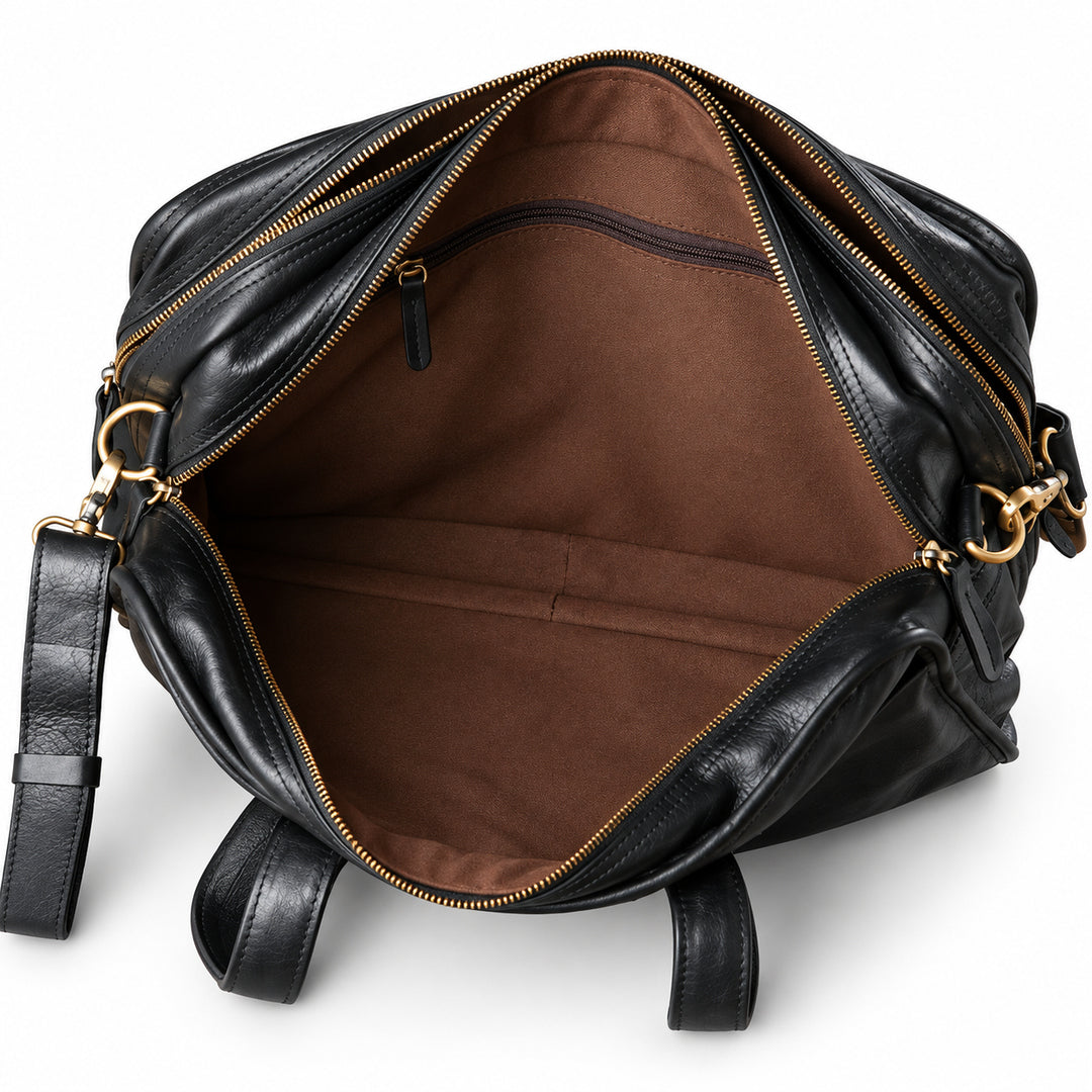 The open black leather briefcase reveals an empty brown-lined compartment with floor seams and an interior zip pocket.