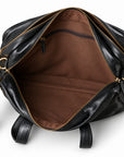 The open black leather briefcase reveals an empty brown-lined compartment with floor seams and an interior zip pocket.
