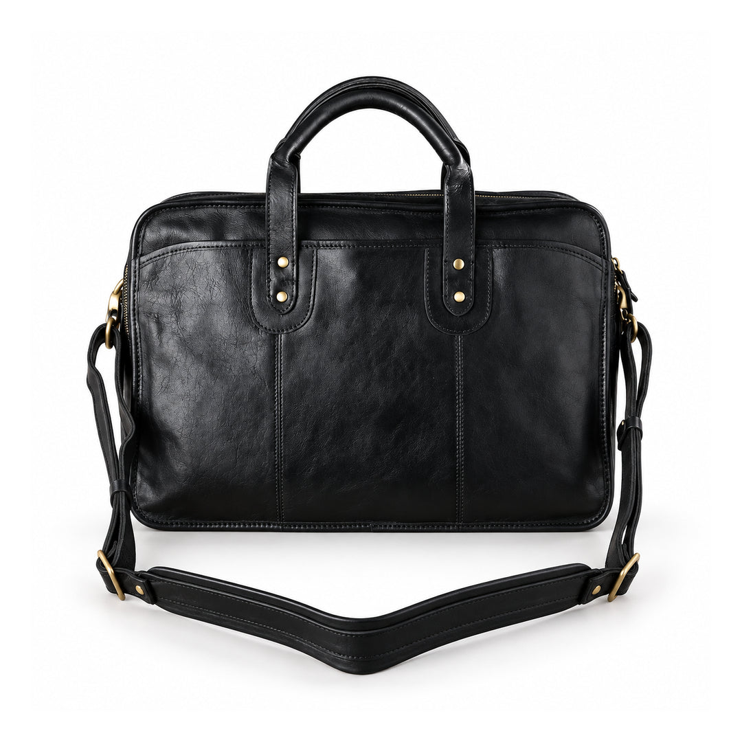 A black leather briefcase is shown with its detachable shoulder strap laid out to reveal the wide padded center and adjustable ends.
