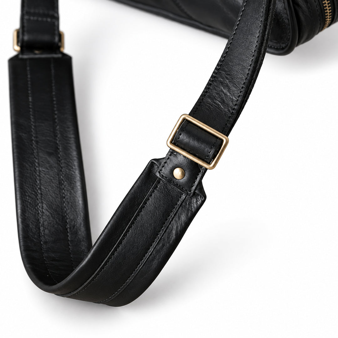 A close-up of the black leather briefcase shoulder strap shows a rectangular adjustment buckle, rivet and padded section.