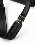 A close-up of the black leather briefcase shoulder strap shows a rectangular adjustment buckle, rivet and padded section.