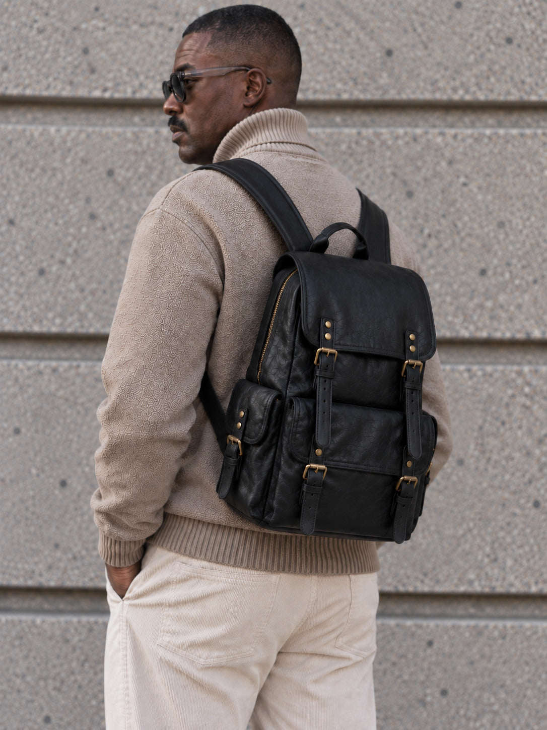 Classic black leather backpack for men with multiple exterior pockets, buckle closures, top handle and adjustable shoulder straps