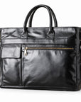 Classic black full-grain leather briefcase at an angle showing front pockets and gold-tone hardware