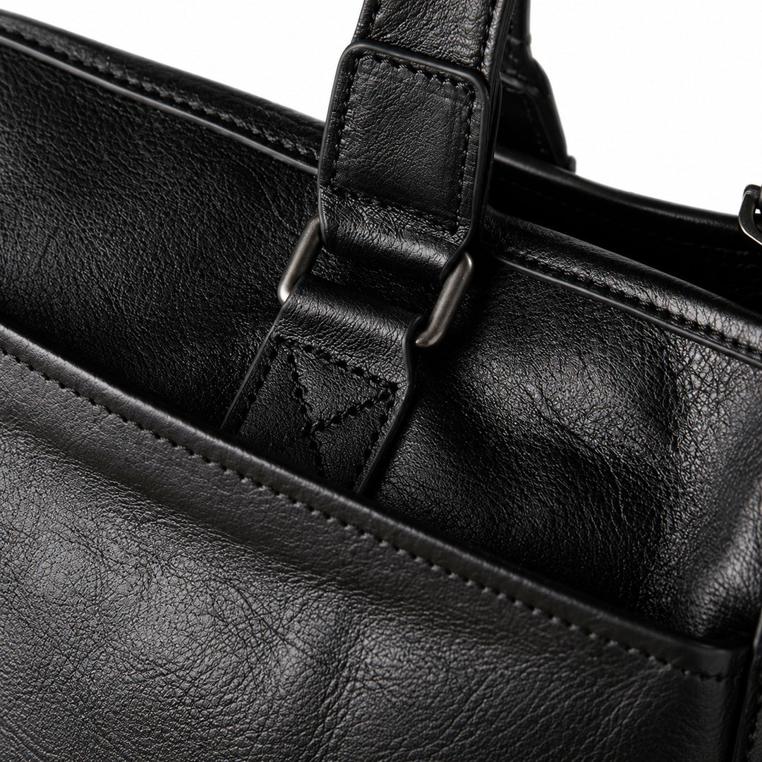 Classic black full-grain leather tote handle attachment with a metal loop and triangular stitching