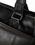 Classic black full-grain leather tote handle attachment with a metal loop and triangular stitching