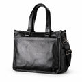 Classic black full-grain leather tote with long handles and a detachable shoulder strap, three-quarter view