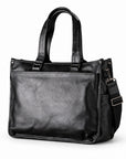 Classic black full-grain leather tote with long handles and a detachable shoulder strap, three-quarter view