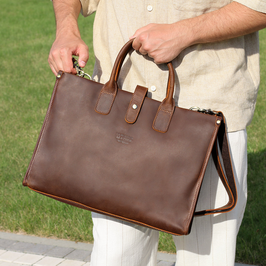 Close-up of Elwards Leather logo and vintage stitching on a brown leather bag.