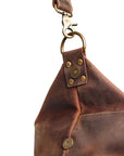Detailed close-up of brass clasp attachment on brown vintage leather bag, highlighting its vintage design elements.