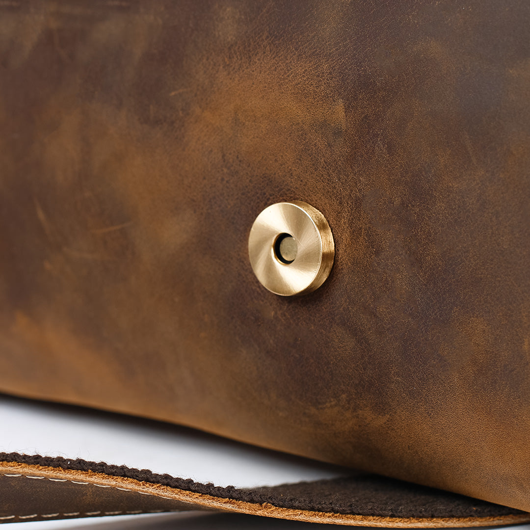 Close-up of a brown leather surface with a gold button