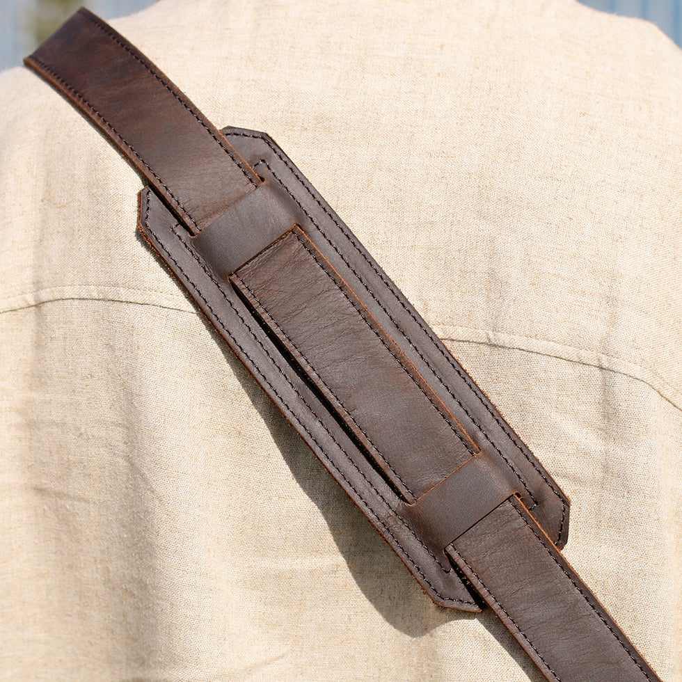 Close-up of a padded leather shoulder strap on a messenger bag, highlighting comfort and durability