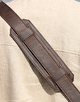 Close-up of a padded leather shoulder strap on a messenger bag, highlighting comfort and durability