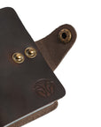 Close-up of brass button closures and embossed logo on a vintage-style leather card holder.