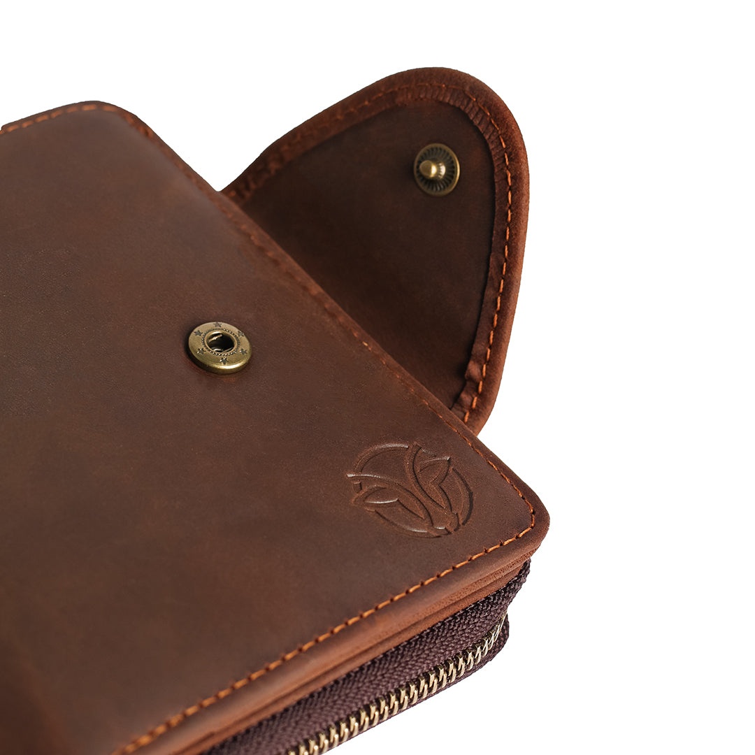 Close-up of a brown leather wallet&#39;s Elwards Leather logo and secure button clasp, showcasing premium craftsmanship.