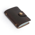 Dark brown leather card holder with button clasp and minimalist design, handcrafted for elegance and durability.