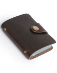 Dark brown leather card holder with button clasp and minimalist design, handcrafted for elegance and durability.