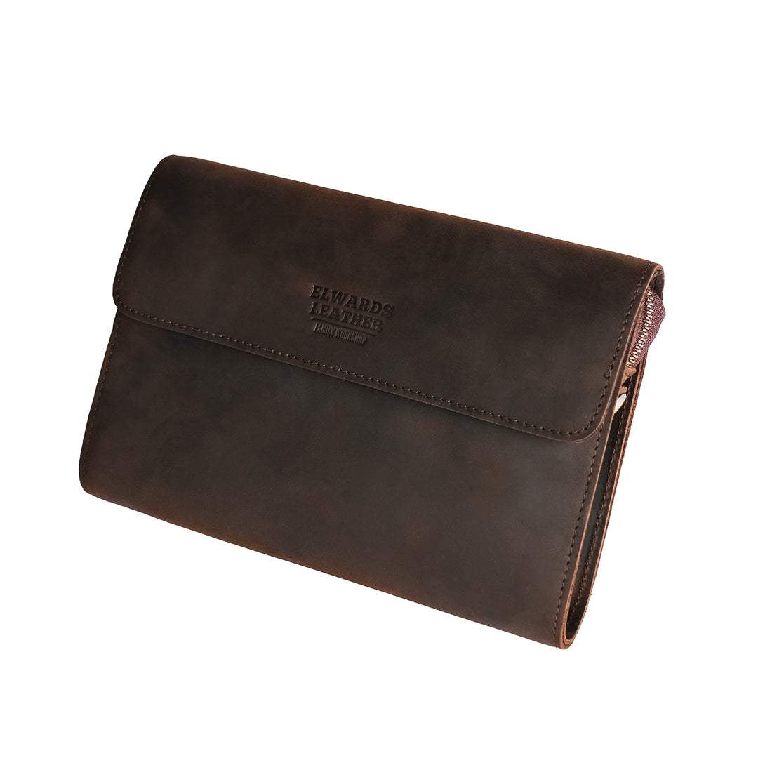 Front angled view of a dark brown men&#39;s leather clutch with a sleek flap design, showcasing Crazy Horse leather.