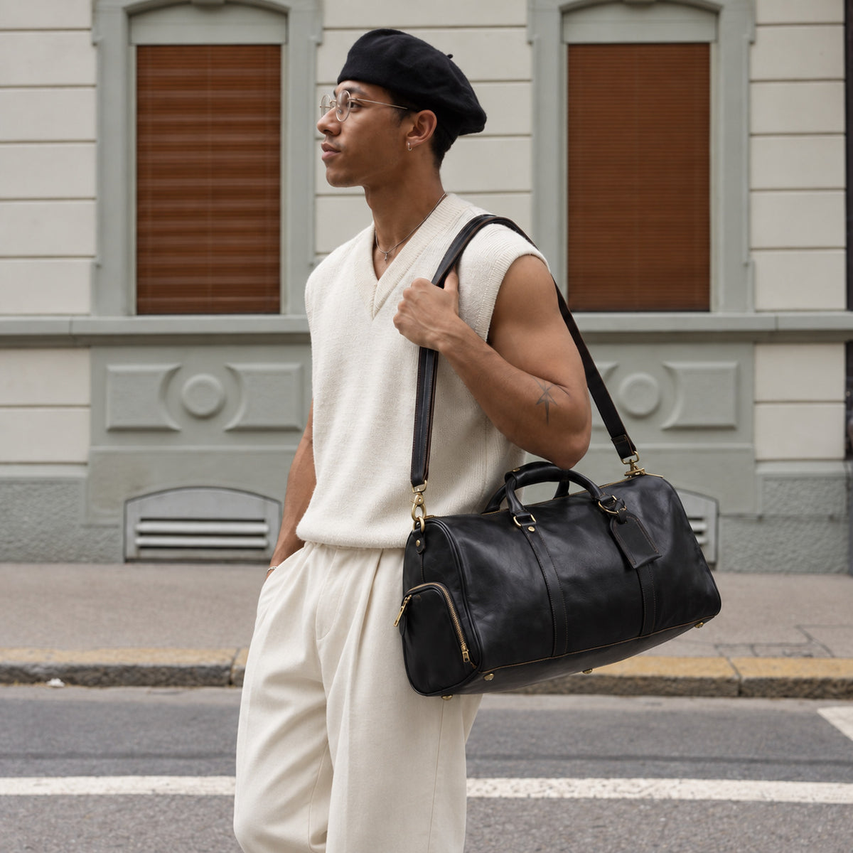 Durable black leather travel duffle bag for men with top handles, adjustable shoulder strap and side zip compartment