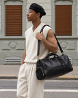 Durable black leather travel duffle bag for men with top handles, adjustable shoulder strap and side zip compartment