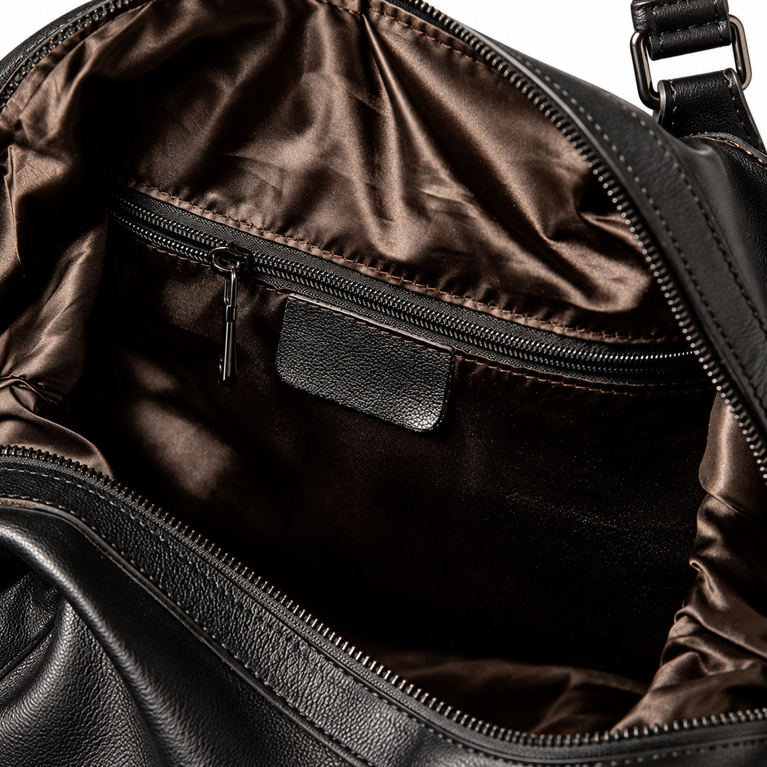 Elegant black full-grain leather duffel bag interior zip pocket with brown fabric lining.