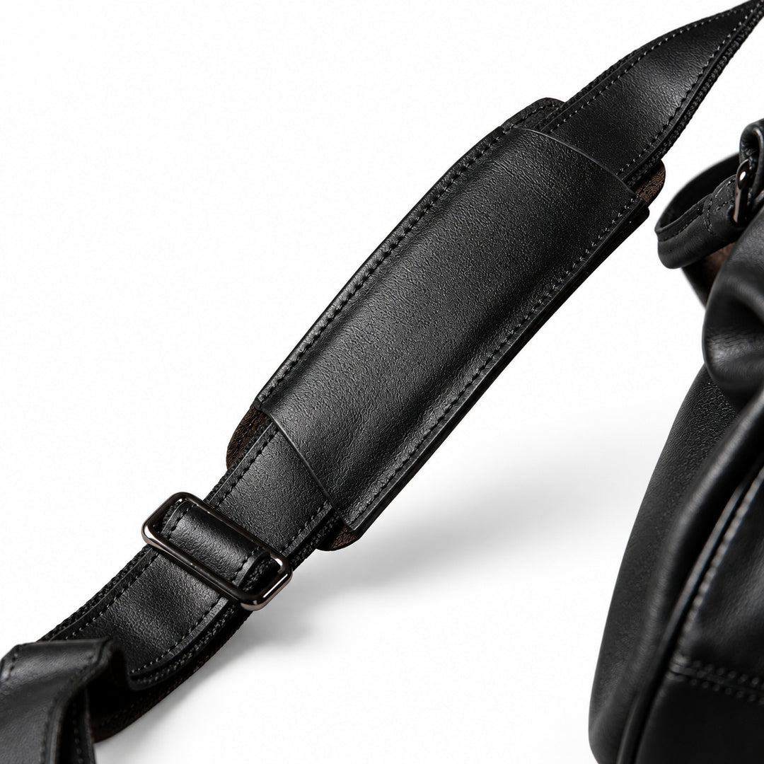 Elegant black full-grain leather duffel bag shoulder strap with leather pad and adjustment slider.