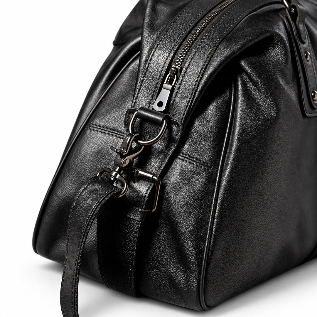 Elegant black full-grain leather duffel bag detail with a detachable swivel clasp and zipper.